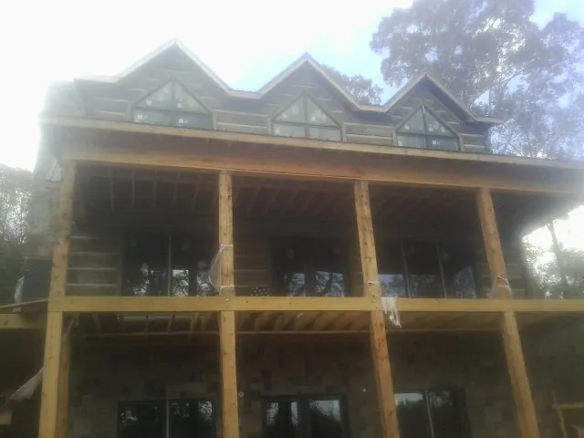 Dormers and porch framing on a large log home under construction — Roof Coating work by our crew in Dike