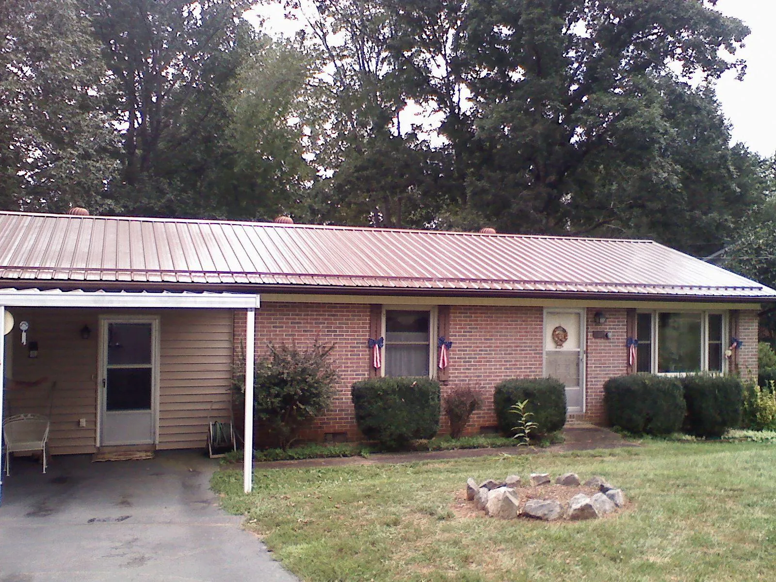 Bronze metal roof and carport on a brick ranch home — Roof Repair work by our crew in Dike