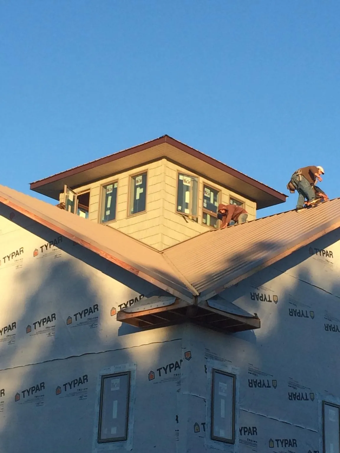 Roofers working around a rooftop cupola on a new metal roof at sunset — Roof Waterproofing in Dike by Roofing Brothers